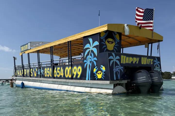 Colorful boat with numbers, American flag, on clear water with blue sky.