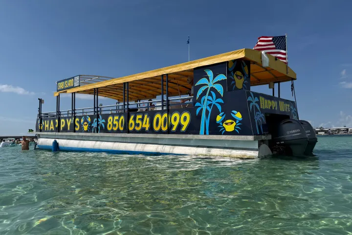 Boat with yellow canopy and U.S. flag in clear water.