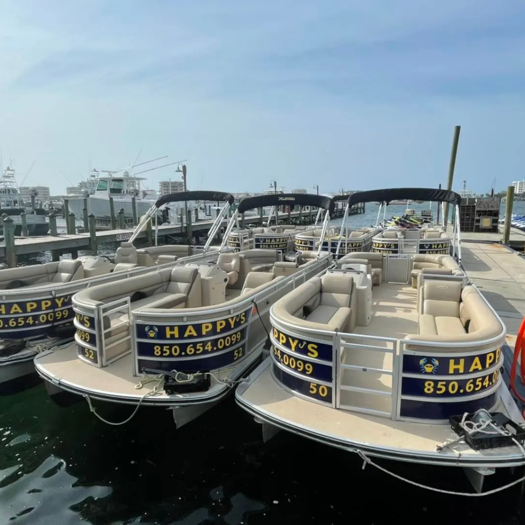Several pontoon boats docked at a marina, labeled 'Happy's' with a phone number.