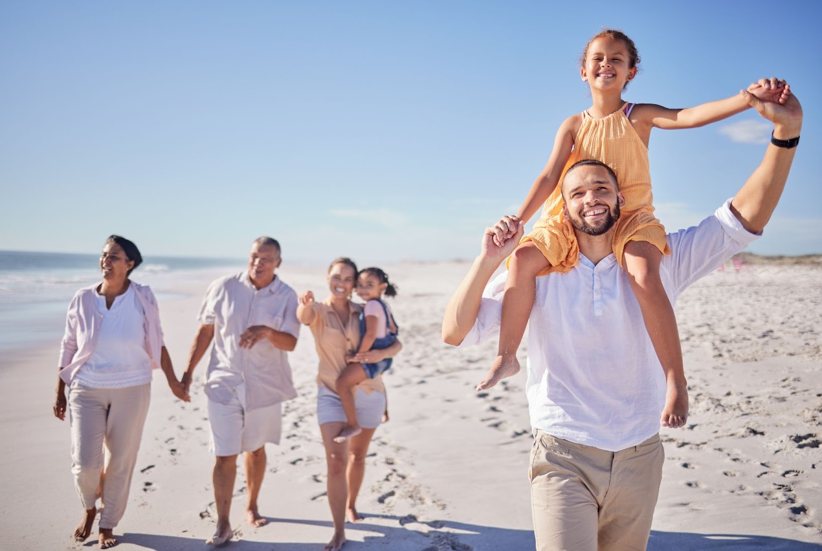 A family walking on the sand close to the shoreline.