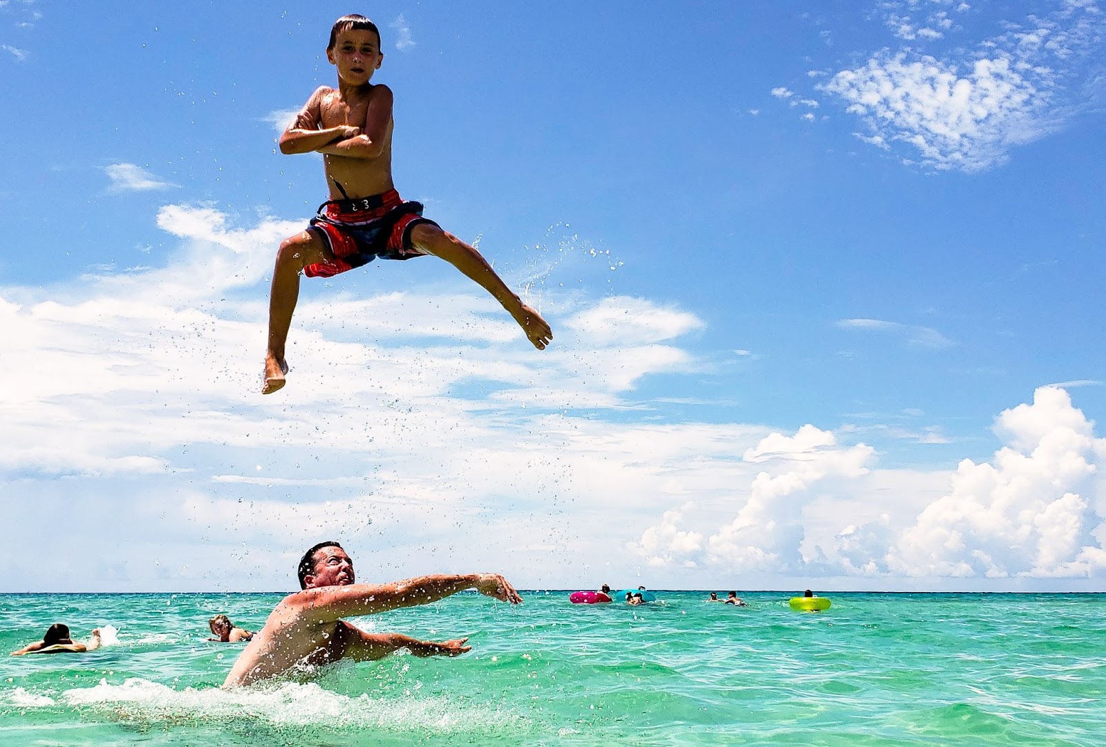 A kid poses a funny angle after his dad throws him in the air.