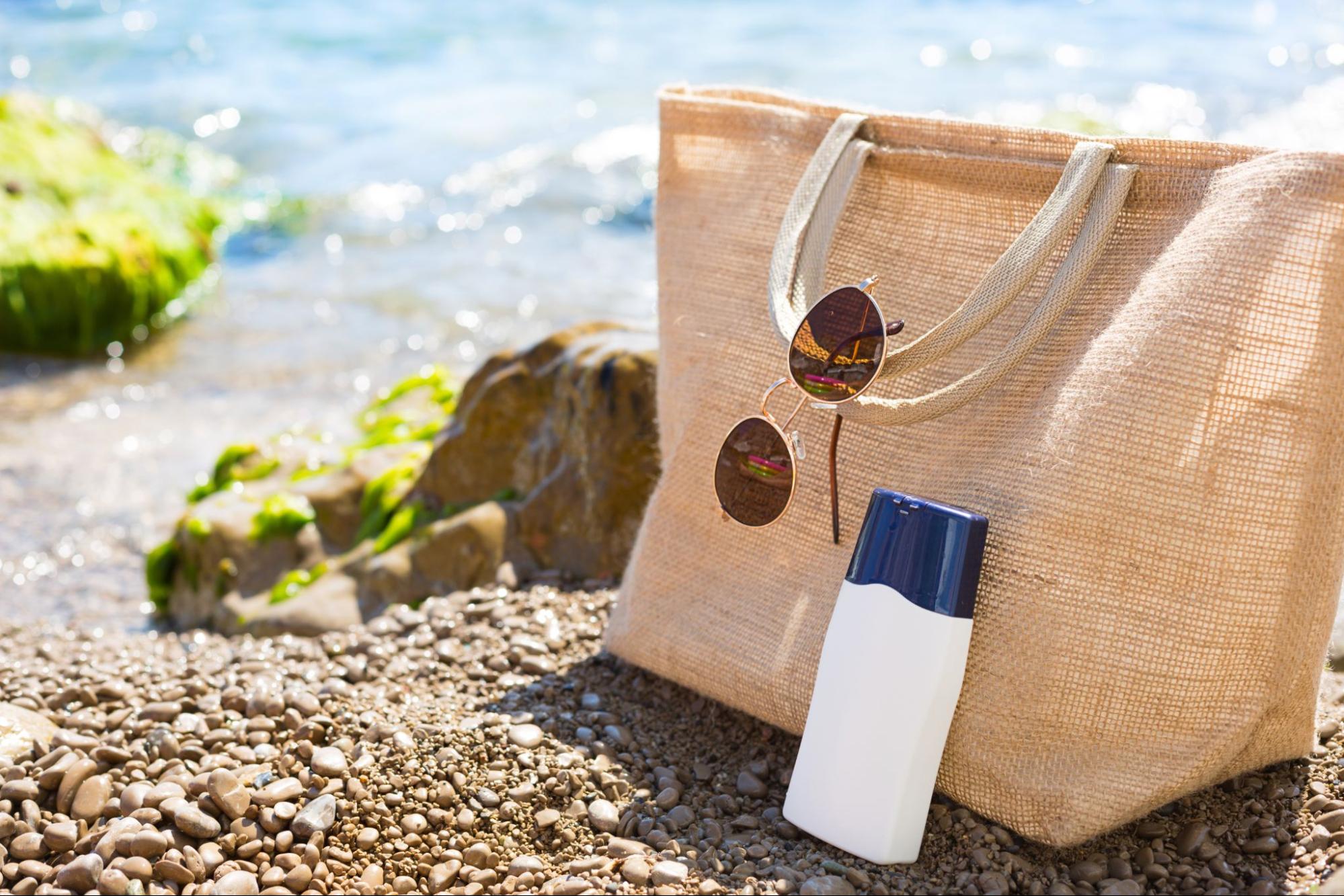 A beach bag by the sea with an eco-friendly tube of sunscree