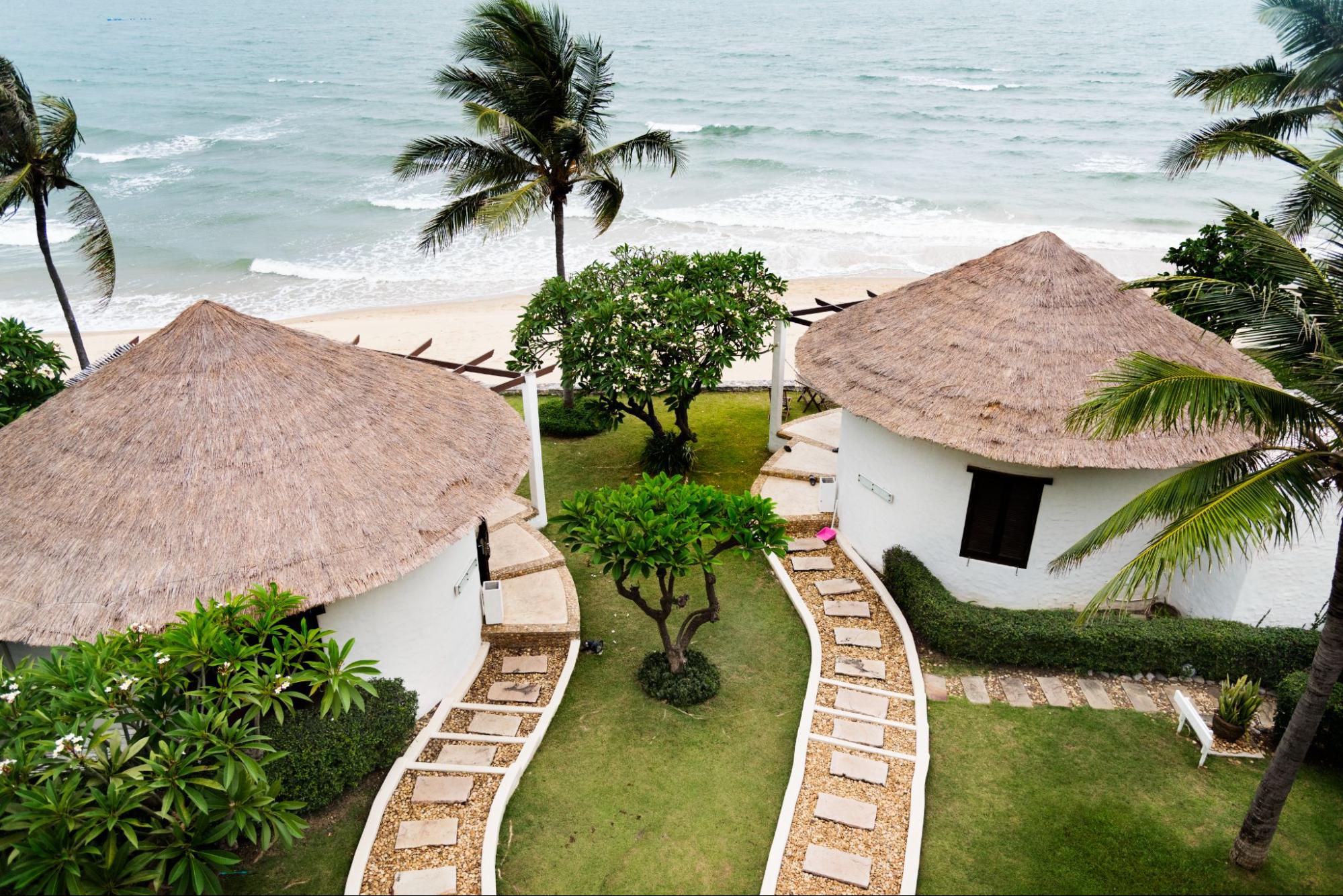 An aerial view of two white bungalows in a beautifully landscaped luxury resort facing the beach. The pristine setting includes lush greenery and well-maintained grounds.

An aerial view of two white bungalows in a beautifully landscaped luxury resort facing the beach. The pristine setting includes lush greenery and well-maintained grounds.

