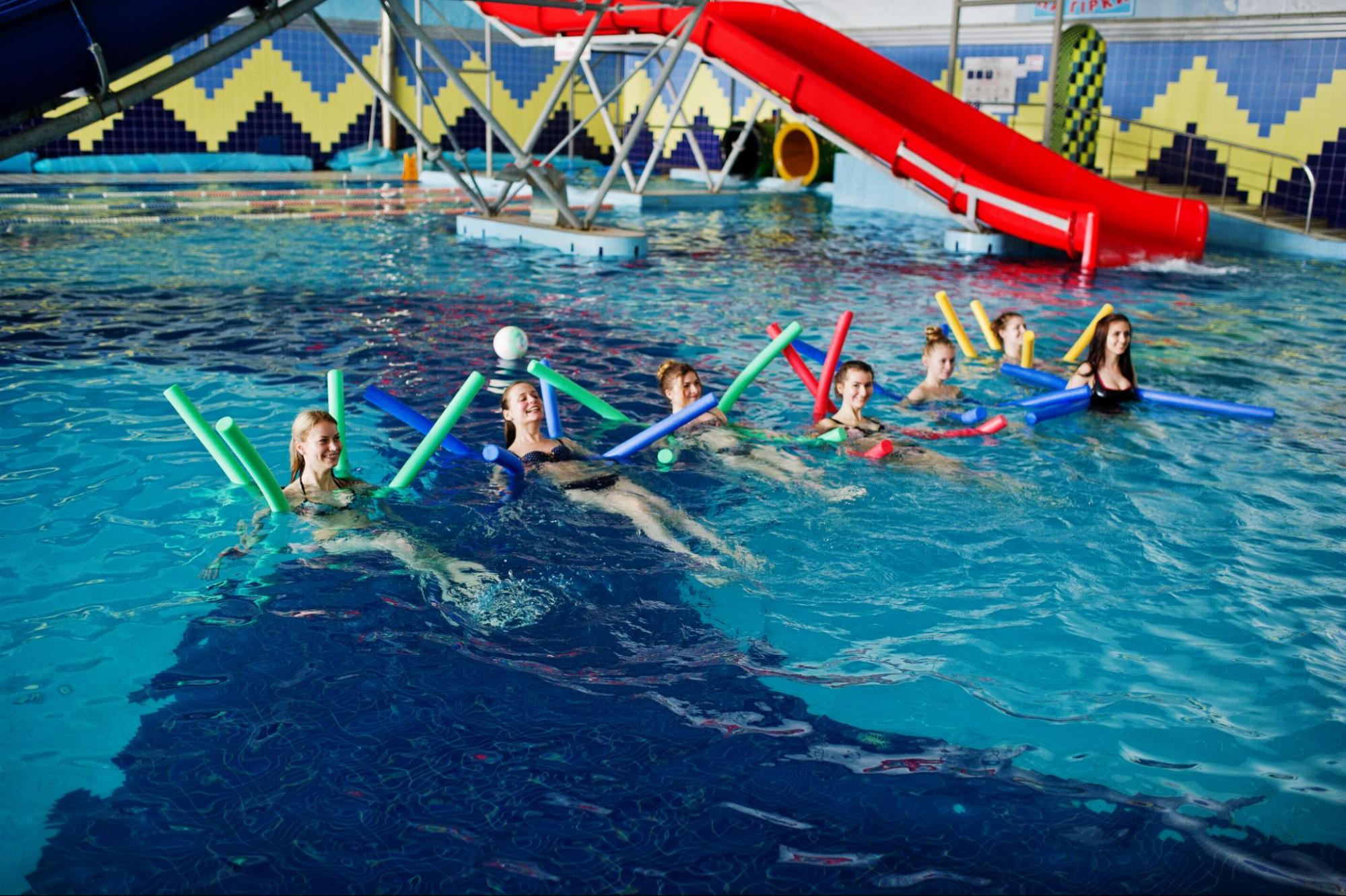 A fitness group is doing aerobic exercises in a swimming pool.