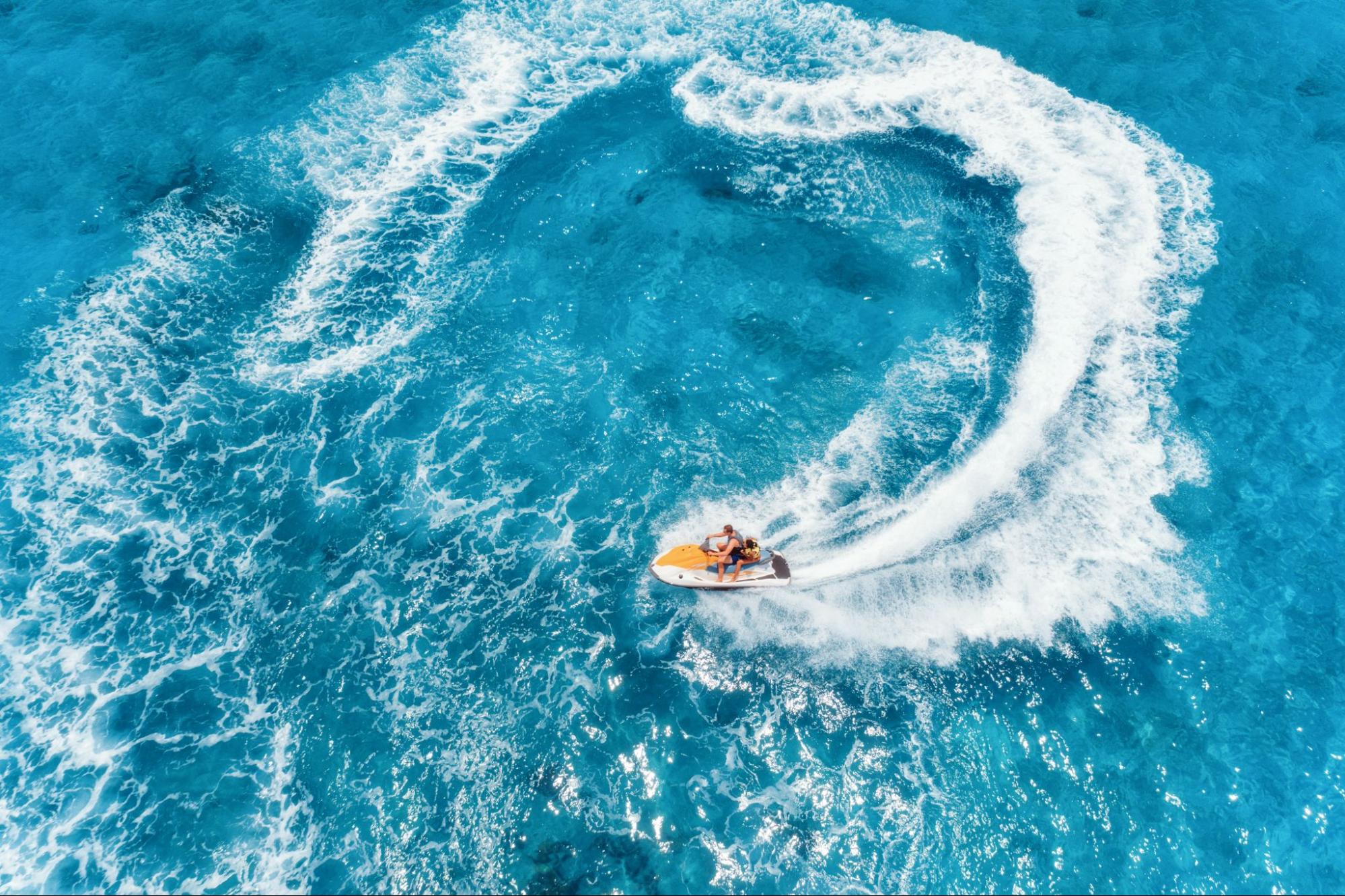 An aerial view of a water scooter floating on clear blue water under the bright sun.