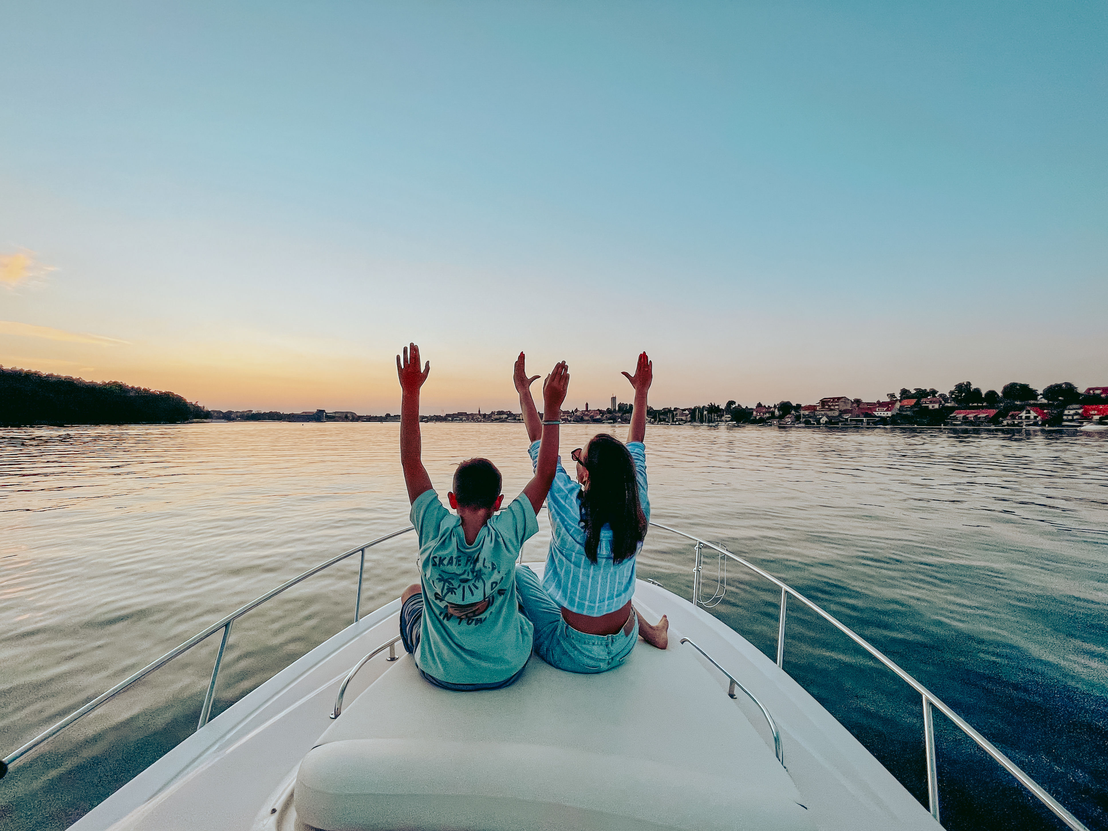 A mom and a son are watching the sunset on a boat.