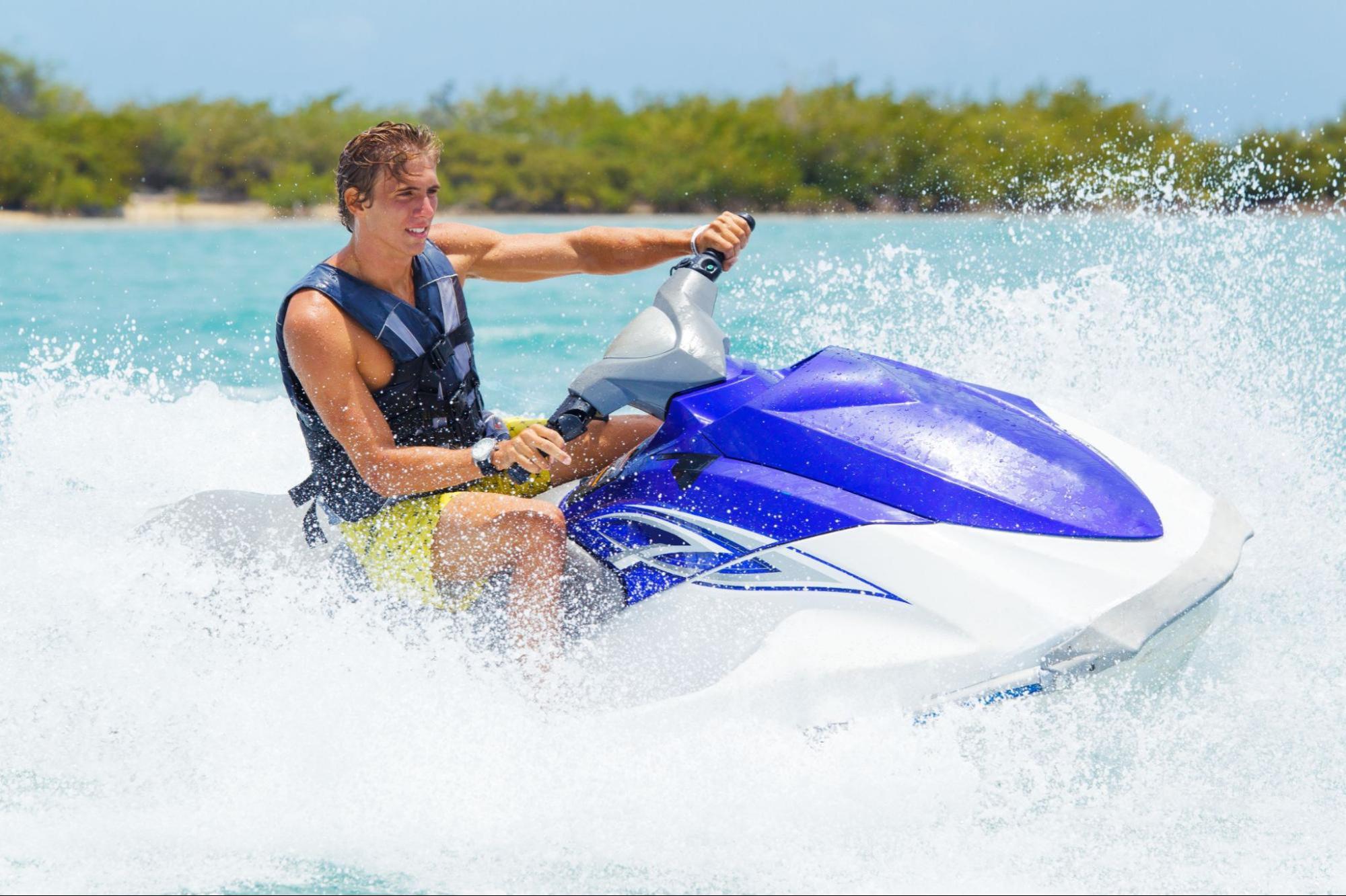 image2_6263de A man wearing a safety vest rides a jet ski with water splashing around.