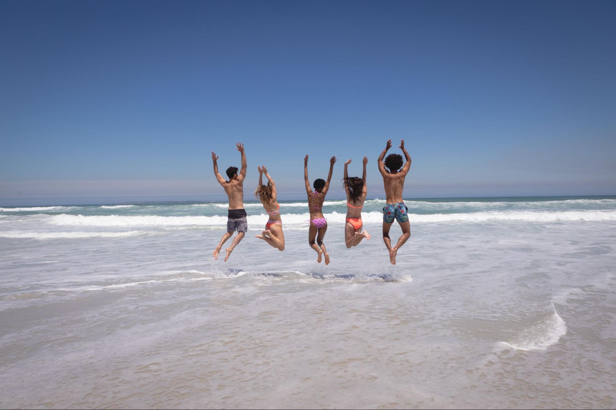 Group of friends jumping in the air at the beach.