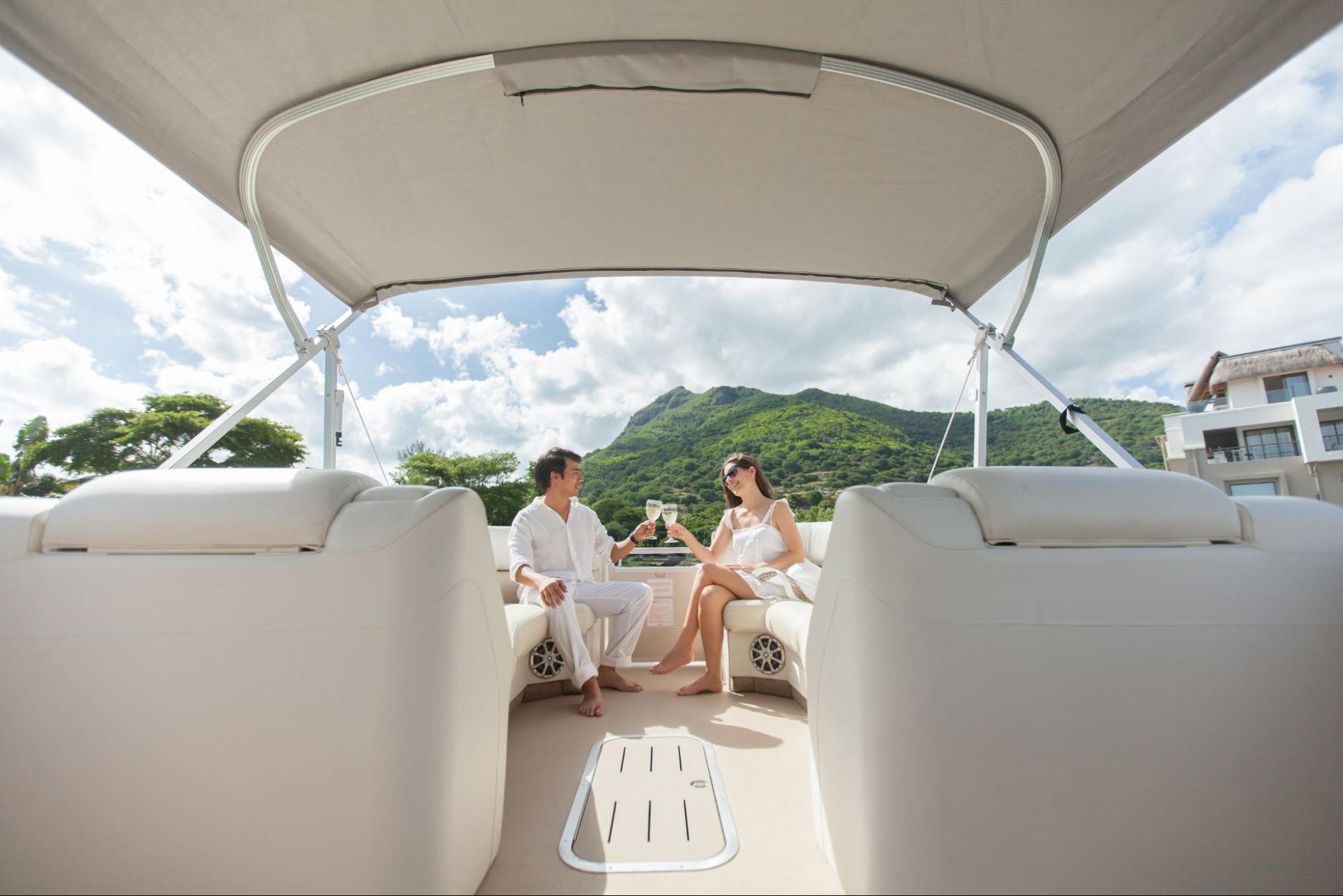 Couple drinking out of glasses on a pontoon boat. 