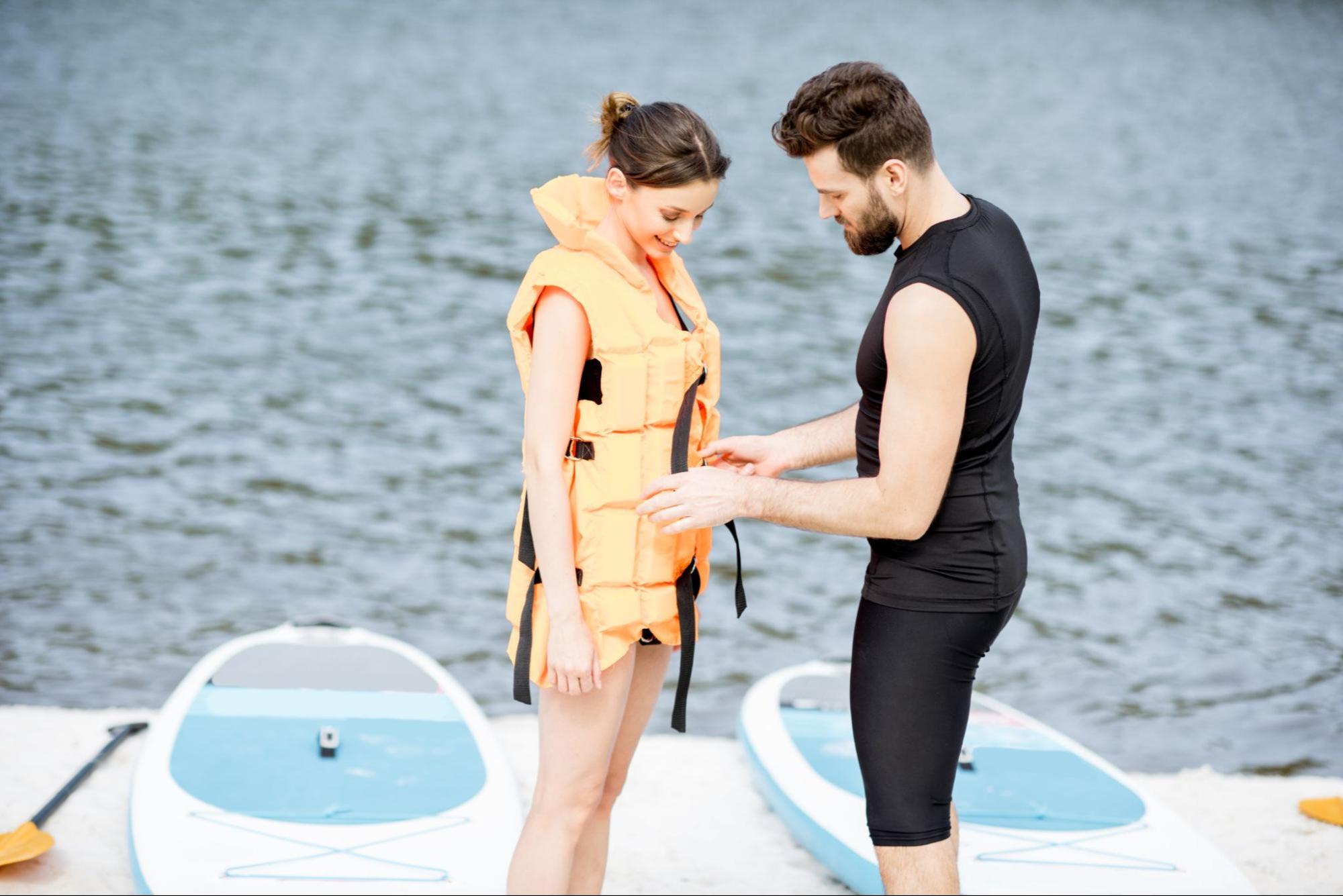 image3_394b73 Man helping a woman put on a lifejacket.